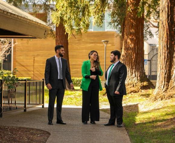 3 students standing on a walk pathway at McGeorge School of Law